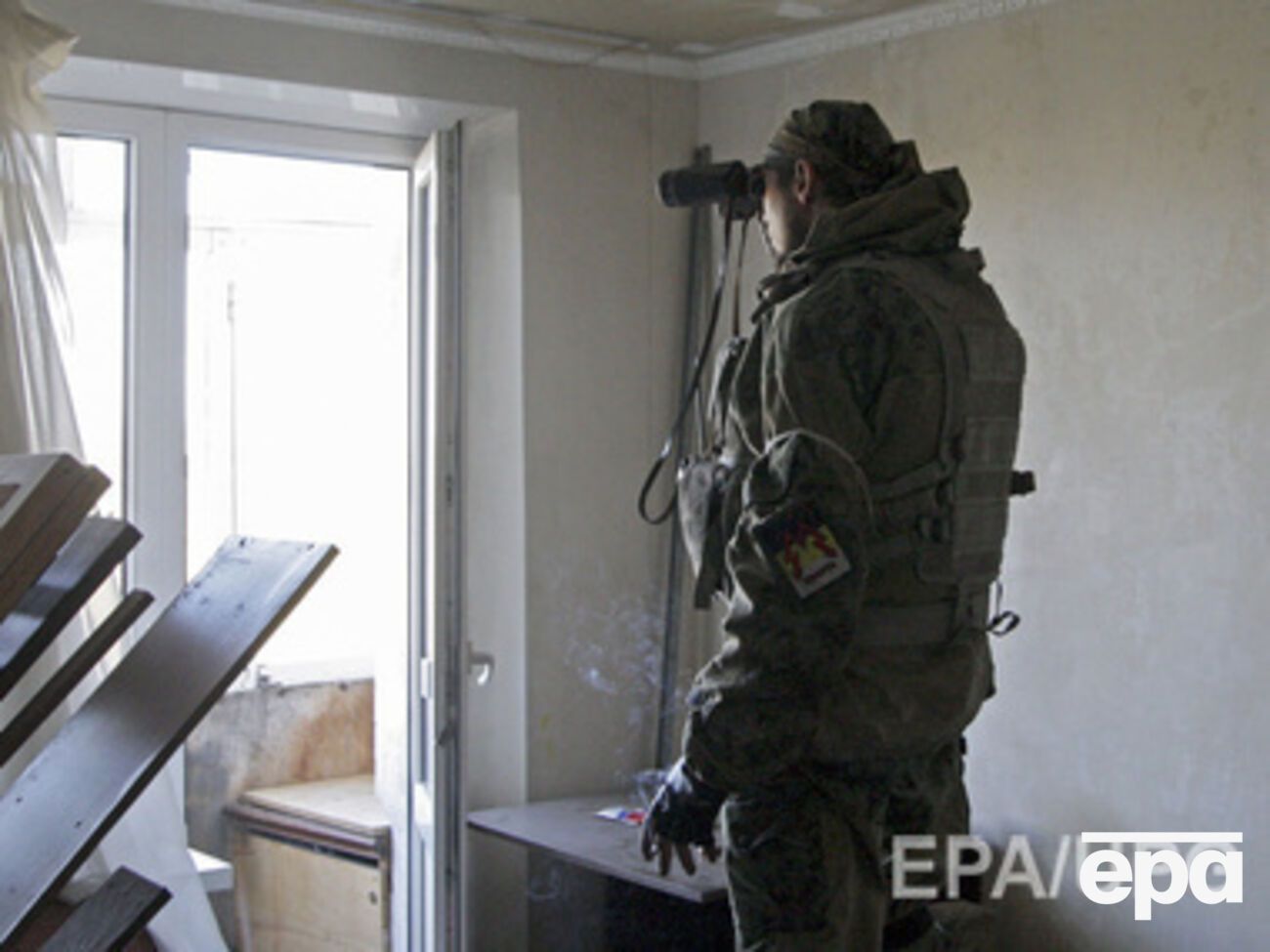Боевик ведет наблюдение за украинскими позициями в аэропорту из окна жилого дома