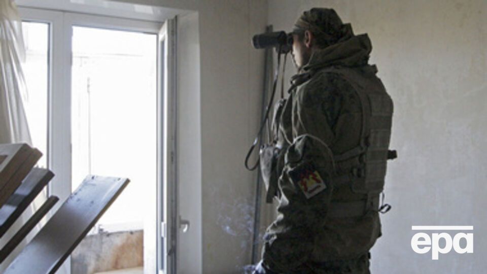 Боевик ведет наблюдение за украинскими позициями в аэропорту из окна жилого дома