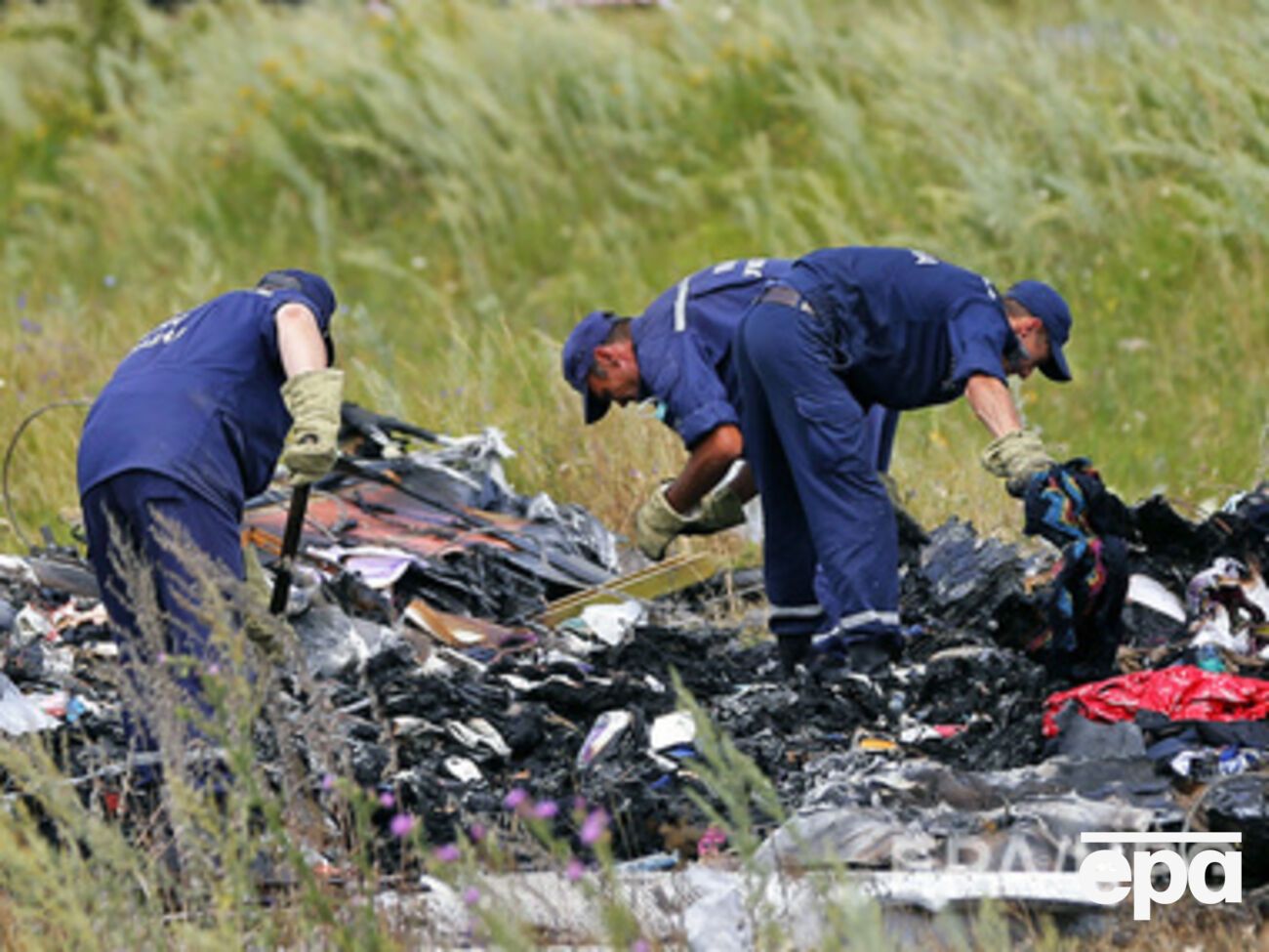 Украинские спасатели осматривают обломки на месте крушения Boeing 777