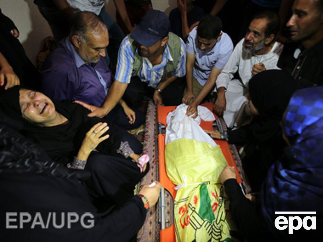 Палестинская женщина плачет над погибшим во время израильской бомбардировки сыном