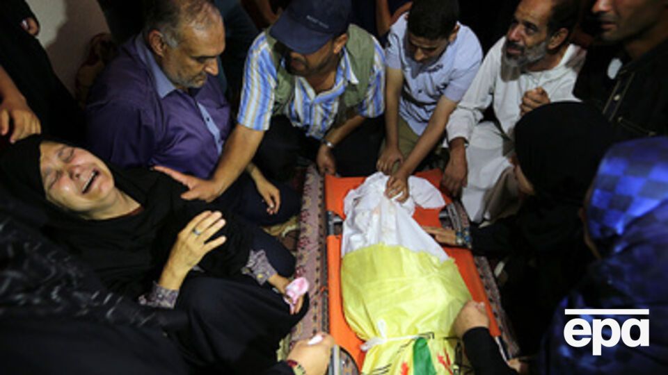 Палестинская женщина плачет над погибшим во время израильской бомбардировки сыном