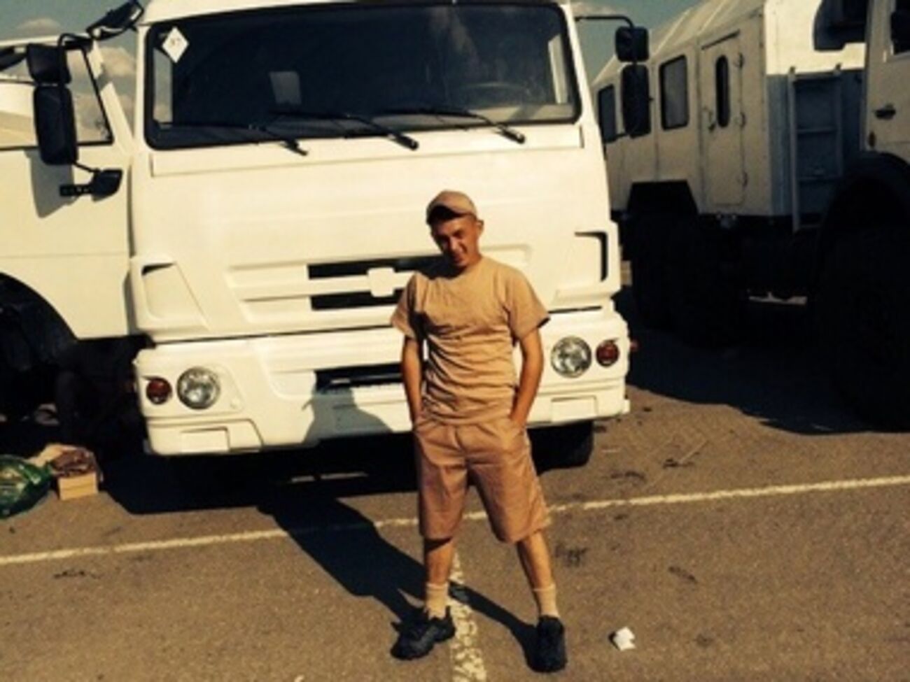 Один из российских военнослужащих позирует на фоне грузовика, перекрашенного в белый цвет, который везет гуманитарную помощь в Украину