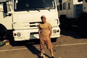 Один из российских военнослужащих позирует на фоне грузовика, перекрашенного в белый цвет, который везет гуманитарную помощь в Украину