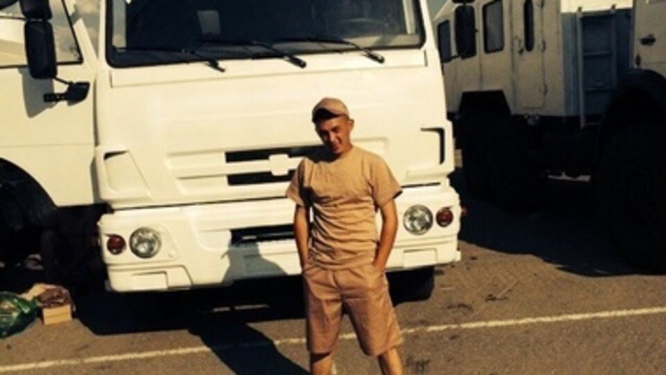 Один из российских военнослужащих позирует на фоне грузовика, перекрашенного в белый цвет, который везет гуманитарную помощь в Украину