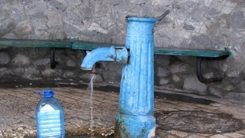 Местные жители набирают воду в бювете возле поселкового рынка