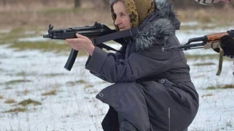 На фотографиях рядом с мужчинами запечатлели старушку в платке, куртке и с оружием в руках