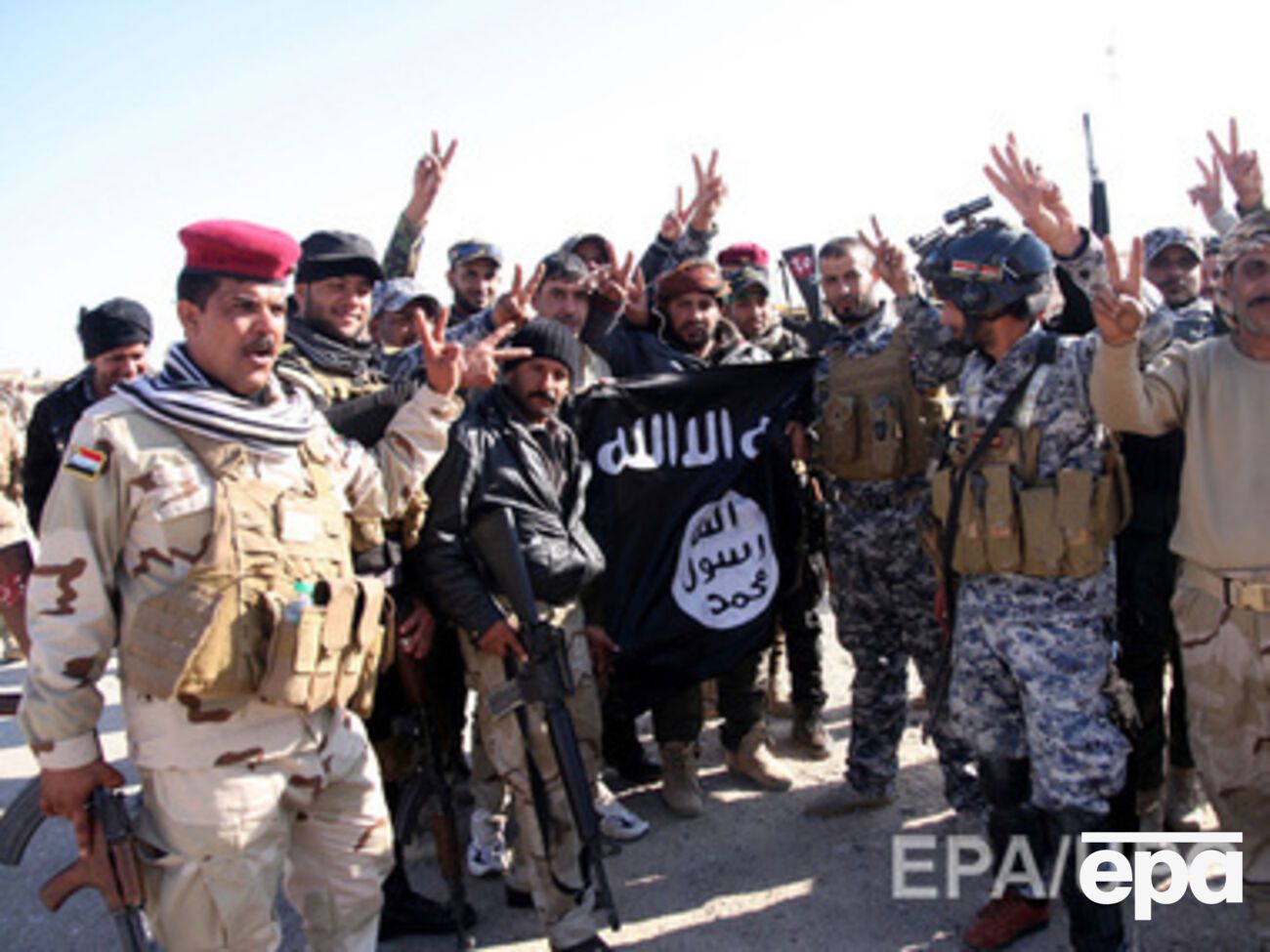 Иракские солдаты несут разорванный флаг "Исламского государства" после освобождения города Аль-Фурат