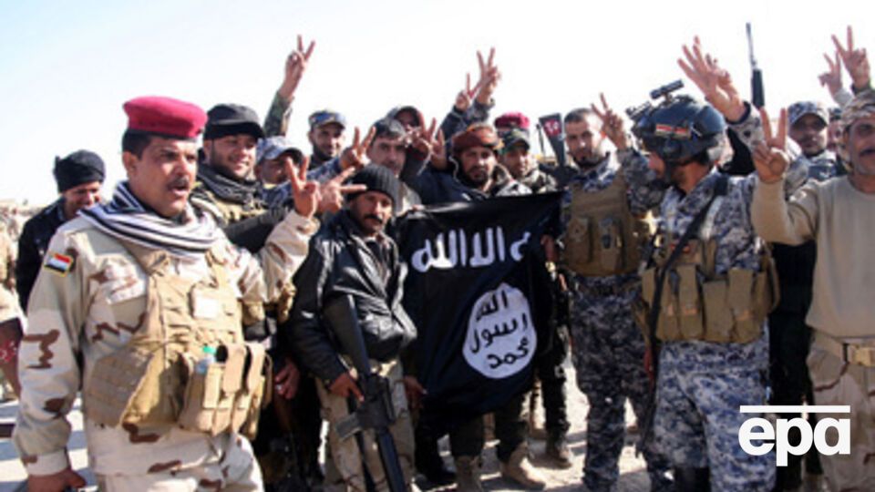 Иракские солдаты несут разорванный флаг "Исламского государства" после освобождения города Аль-Фурат