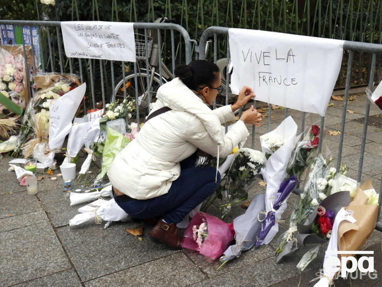 К полицейскому ограждению у театра Bataclan люди приносят цветы и свечи