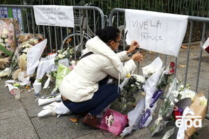 К полицейскому ограждению у театра Bataclan люди приносят цветы и свечи