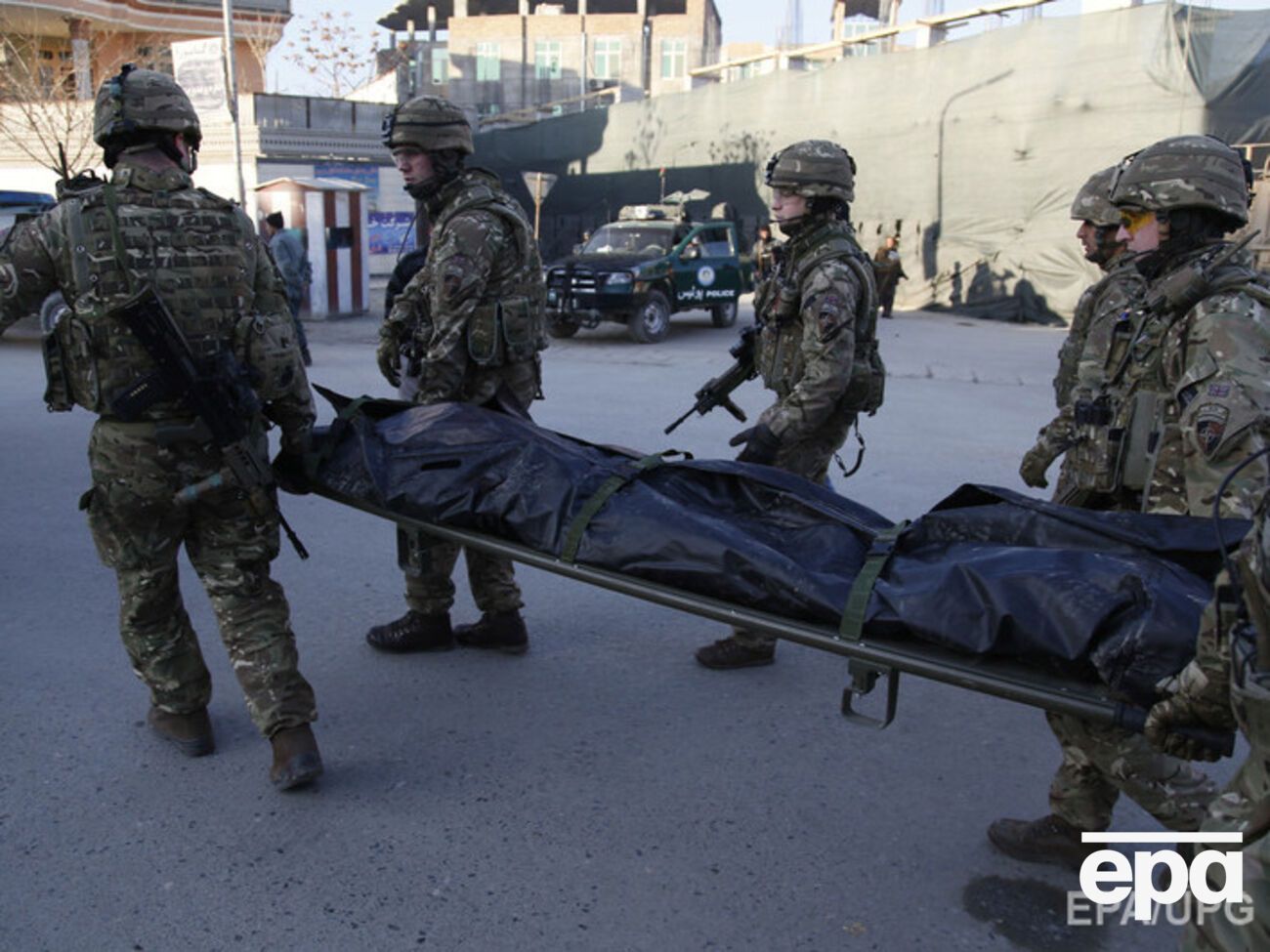 Британские военные, пришедшие на помощь, выносят тело погибшего испанского полицейского
