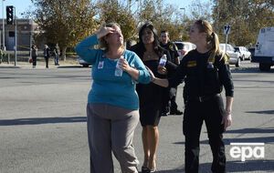 Полицейские выводят сотрудницу центра из здания, в котором произошла стрельба