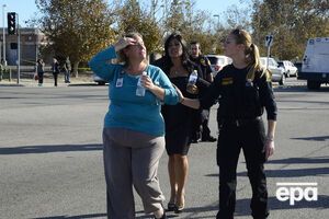 Полицейские выводят сотрудницу центра из здания, в котором произошла стрельба