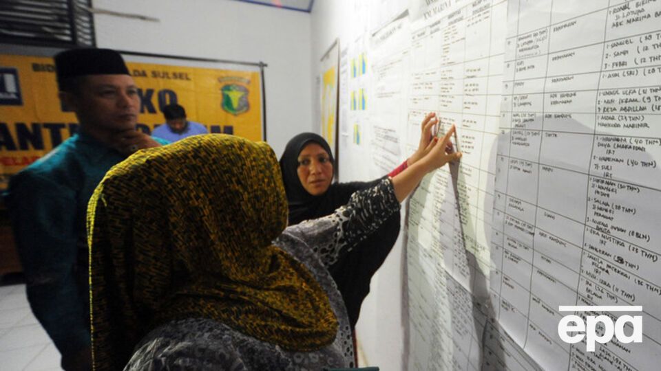 Родственники проверяют имена близких в списках погибших и пропавших в кризисном центре на острове Сулавеси