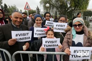 Участники марша против терроризма держат плакаты, гласящие "Посетите Тунис"