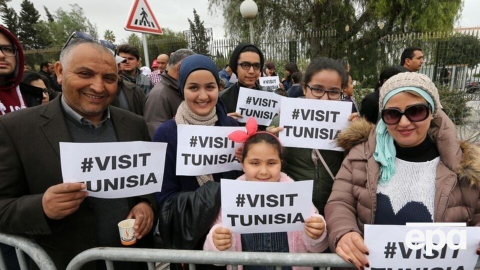 Участники марша против терроризма держат плакаты, гласящие "Посетите Тунис"