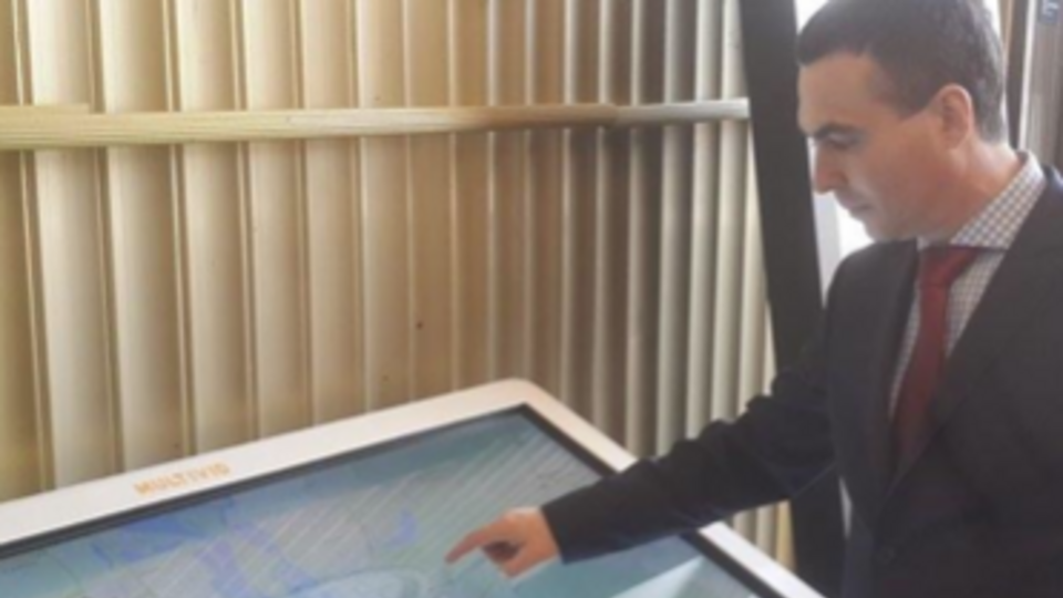 Глава КП "Киевпастранс" Сергей Майзель рядом с мультимедийным табло, которое будет установлено в зале фуникулера