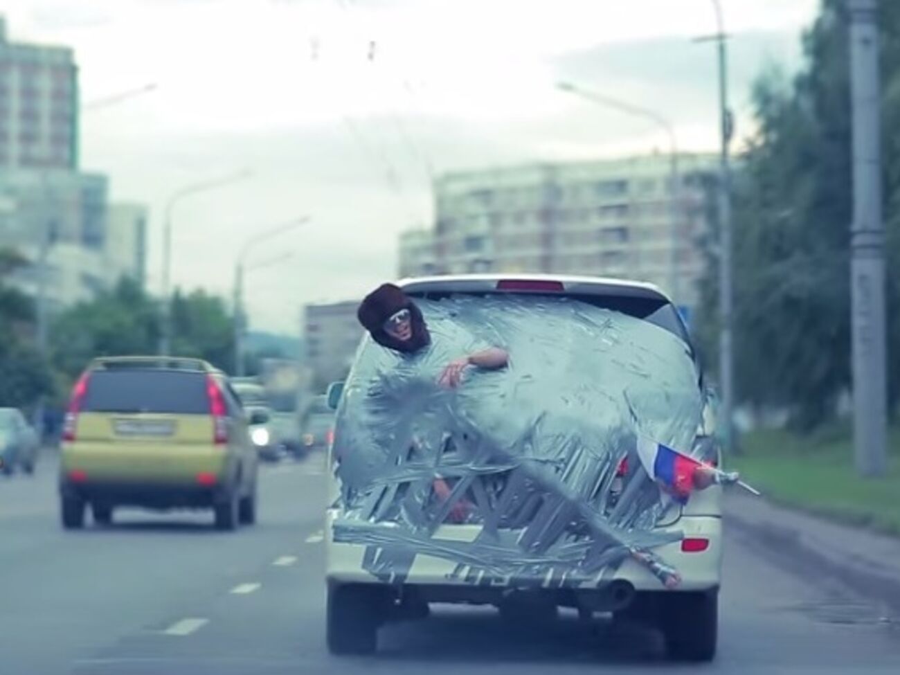 Голого россиянина приклеили скотчем к автомобилю и возили по городу, надев на него ушанку и приклеив к ноге флаг РФ. Видео
