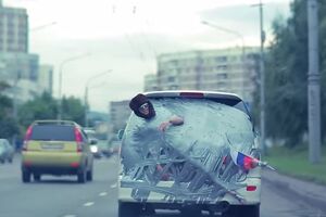 Голого россиянина приклеили скотчем к автомобилю и возили по городу, надев на него ушанку и приклеив к ноге флаг РФ. Видео
