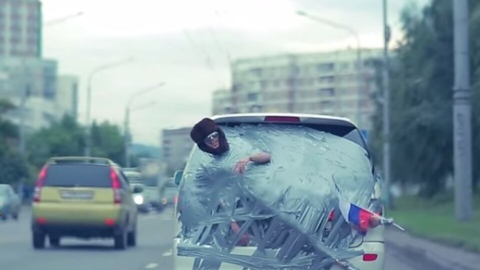 Голого россиянина приклеили скотчем к автомобилю и возили по городу, надев на него ушанку и приклеив к ноге флаг РФ. Видео
