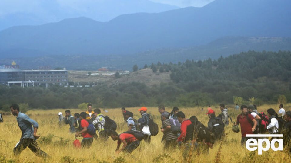 Мигранты, прорвавшиеся через колючую проволоку, бегут по полю в сторону македонского города Гевгелия