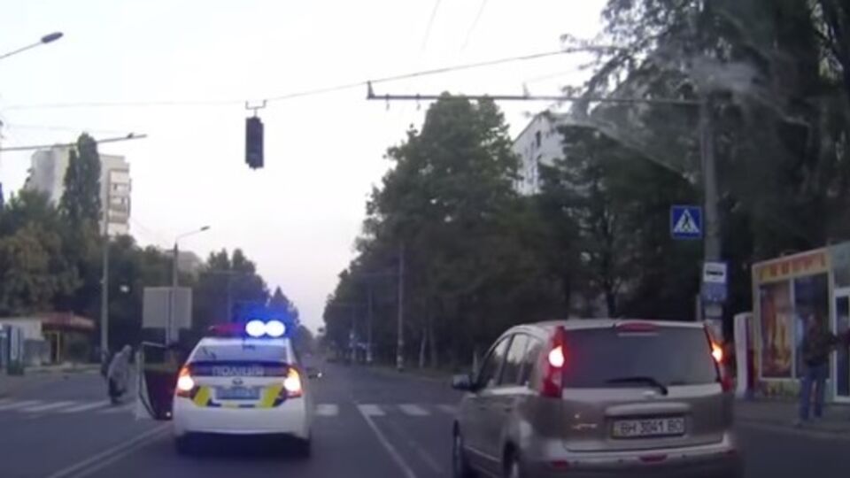 Полицейский остановился на дороге, чтобы перевести через дорогу старушку