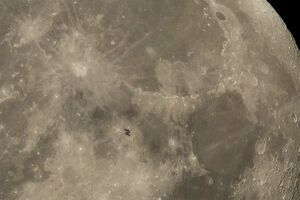 Станция едва видна на фоне Луны