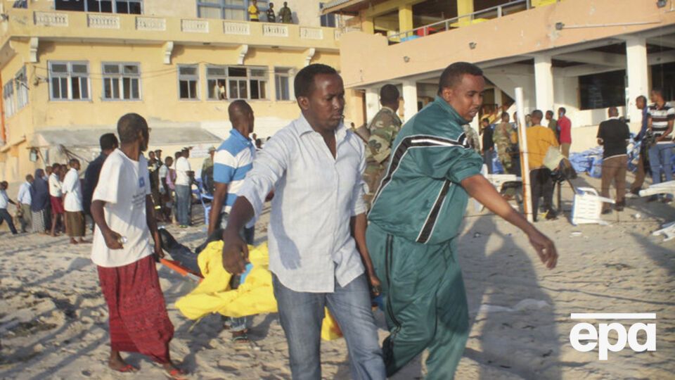 Мужчины несут тело погибшего при нападении террористов на ресторан