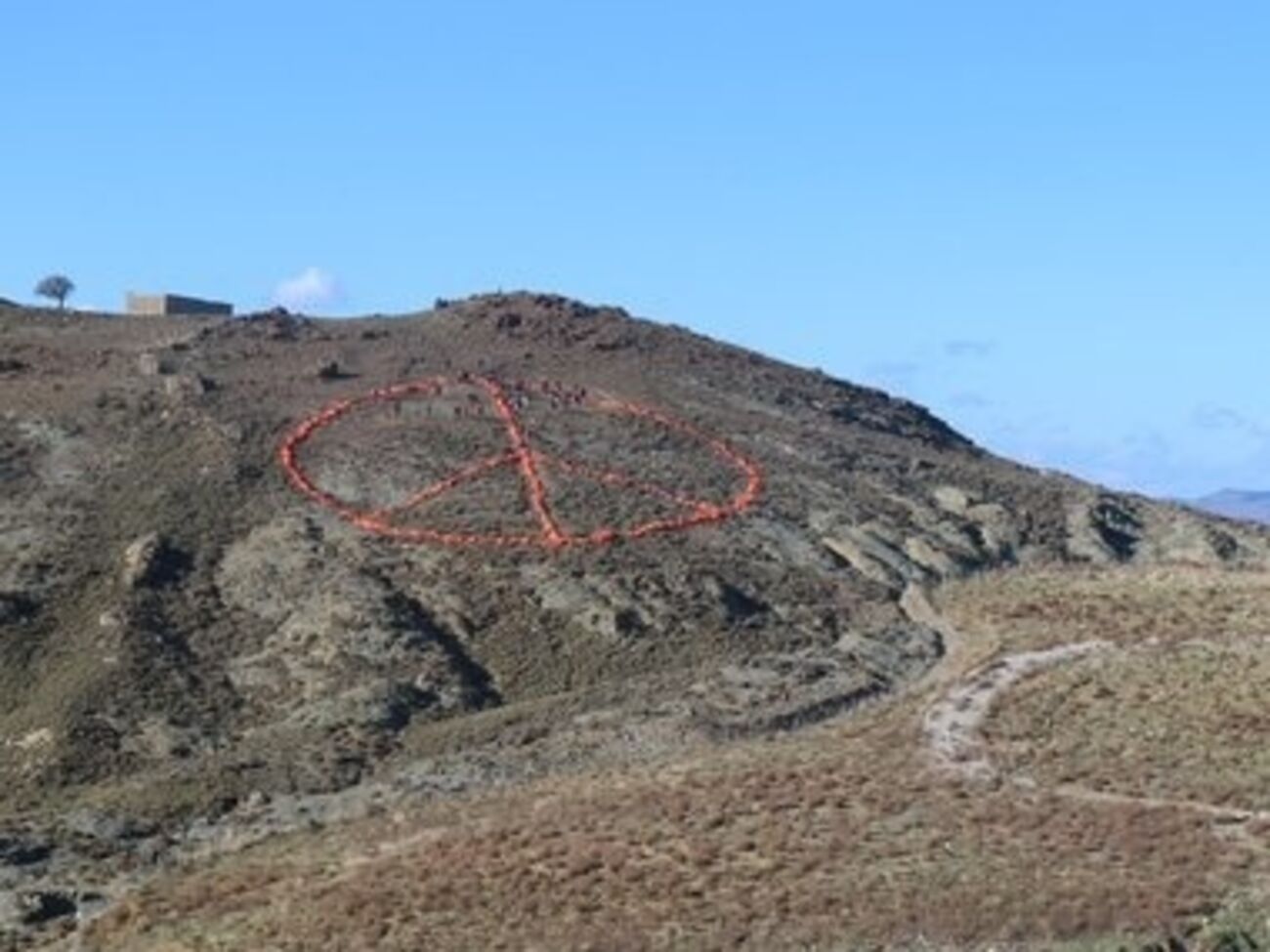 Знак выложен на холме у моря