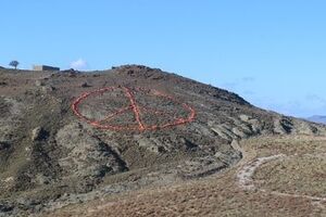 Знак выложен на холме у моря