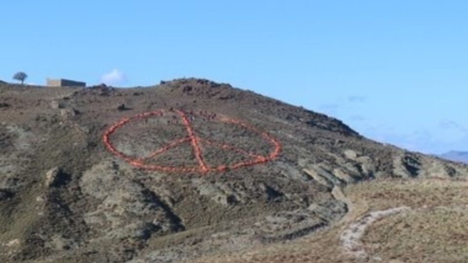 Знак выложен на холме у моря