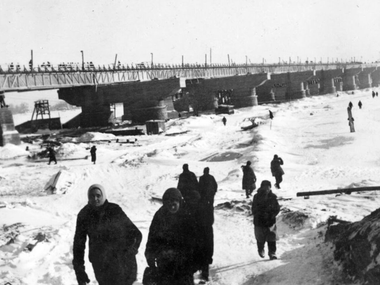 Киевляне переходят Днепр по льду мимо строящегося моста фон Рейхенау. Зима 1941–1942 годов