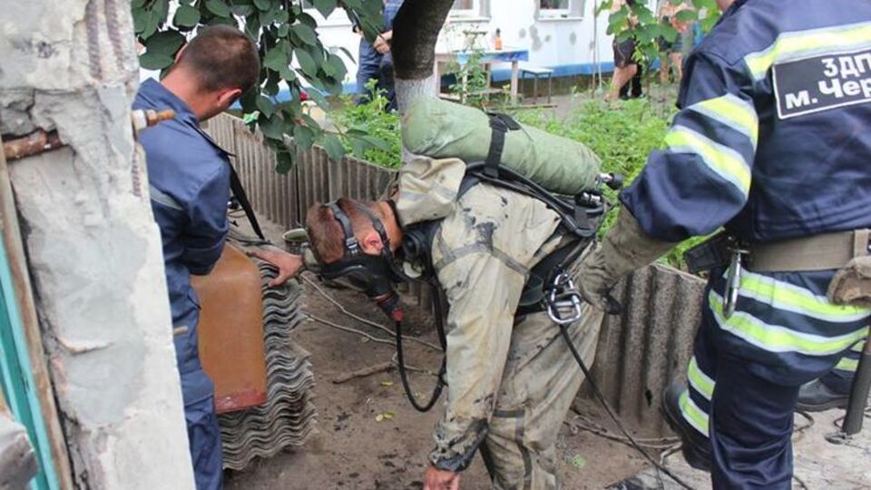 Спасатели в защитных костюмах и в противогазах достали тела погибших