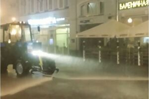 Поливальная машина моет улицу Арбат в Москве во время сильного ливня