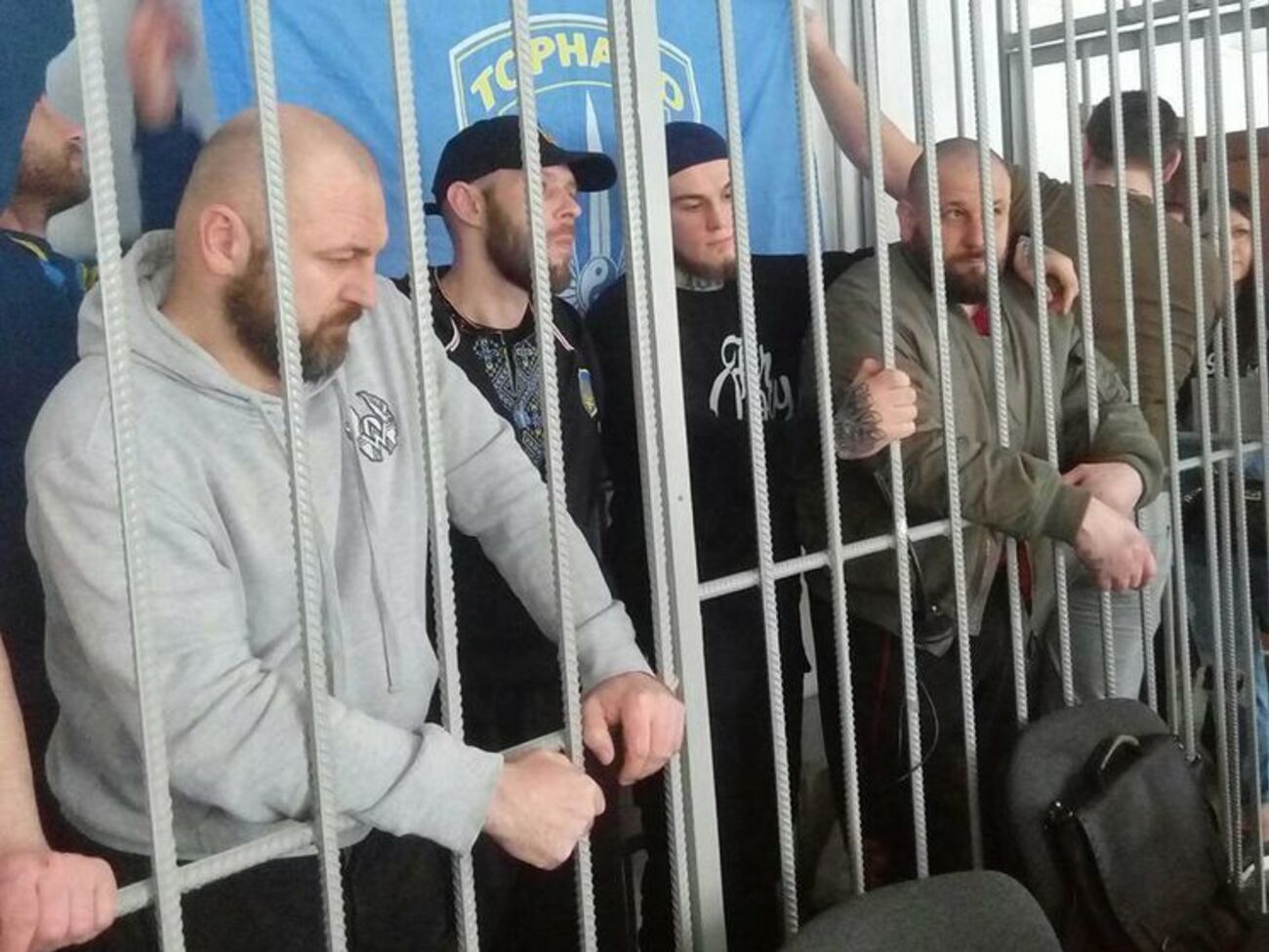 Первых торнадовцев задержали 14 месяцев назад. Сейчас в СИЗО 12 бойцов роты. Военная прокуратура обвиняет их в "насилии и мародерстве". "Торнадо" настаивает: уголовное дело появилось после того, как они в зоне АТО начали блокировать поезда с контрабандой