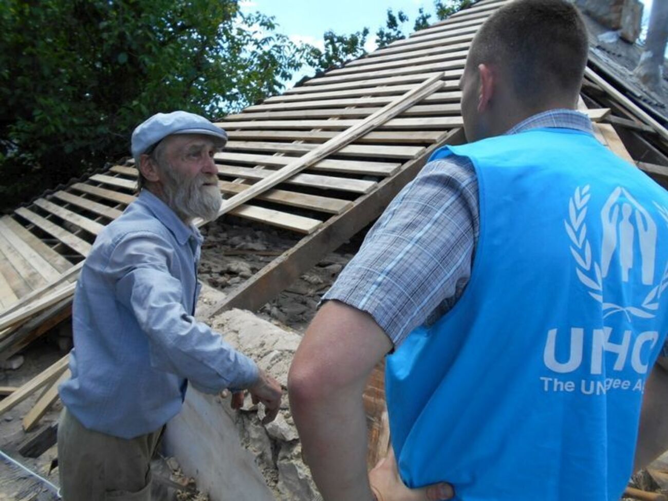 Представители ООН беседуют с жителем Луганской области, дом которого частично разрушен