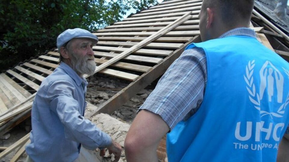 Представители ООН беседуют с жителем Луганской области, дом которого частично разрушен