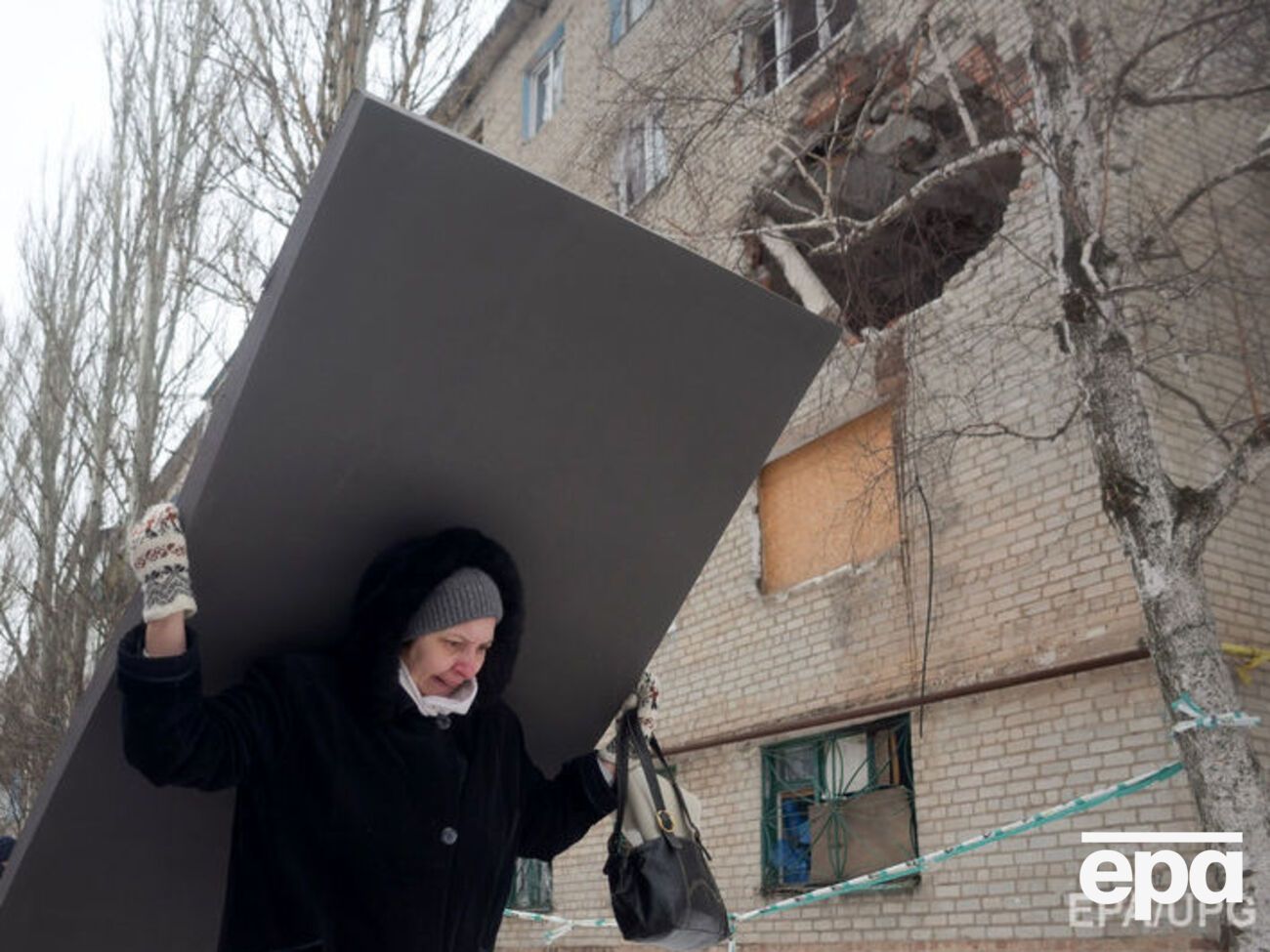 Жительница Авдеевки несет строительные материалы для ремонта своего дома после обстрела