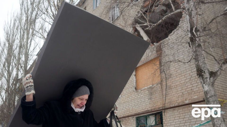Жителька Авдіївки несе будівельні матеріали для ремонту свого будинку після обстрілу