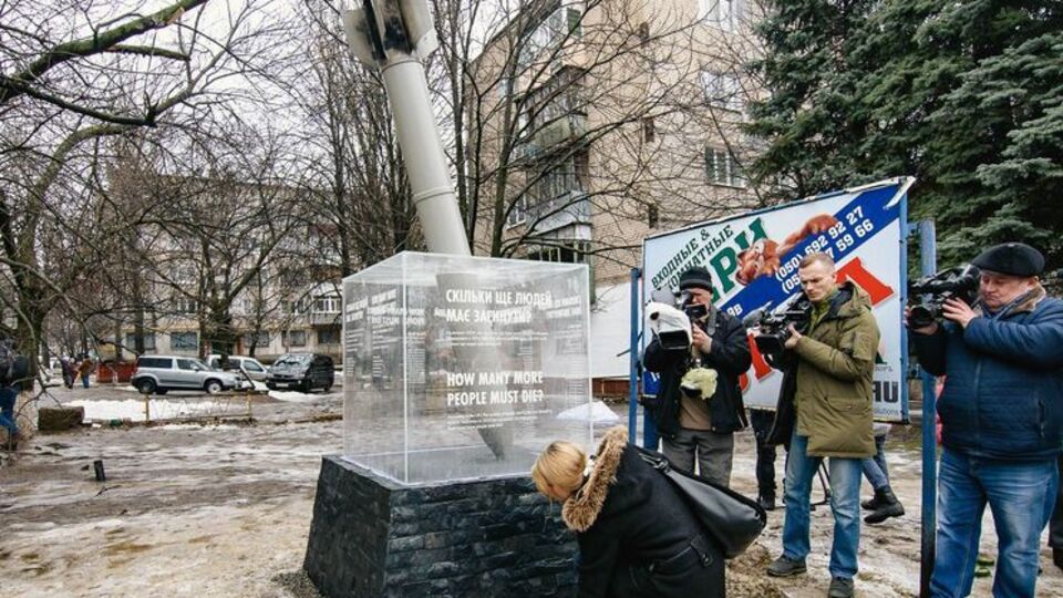 Мемориал представляет из себя прилетевший снаряд и стеклянный куб с надписью: "Сколько людей еще должны погибнуть?"
