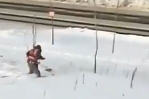 Коммунальщик подстригает траву по колено в снегу