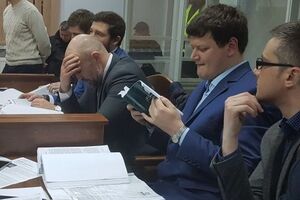 Мангера (на фото со склоненной головой) защищает пять адвокатов