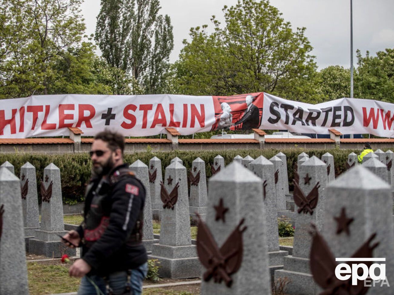 Демонстранты растянули вдоль стены кладбища плакат с надписью: "Гитлер и Сталин начали Вторую мировую войну"