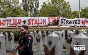 Демонстранты растянули вдоль стены кладбища плакат с надписью: "Гитлер и Сталин начали Вторую мировую войну"