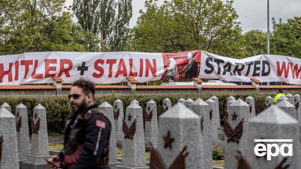 Демонстранты растянули вдоль стены кладбища плакат с надписью: "Гитлер и Сталин начали Вторую мировую войну"