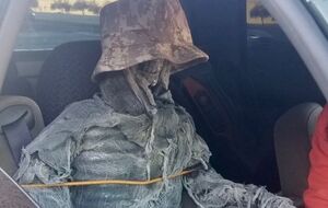 Мужчина одел макет в кепку и обмотал его марлей