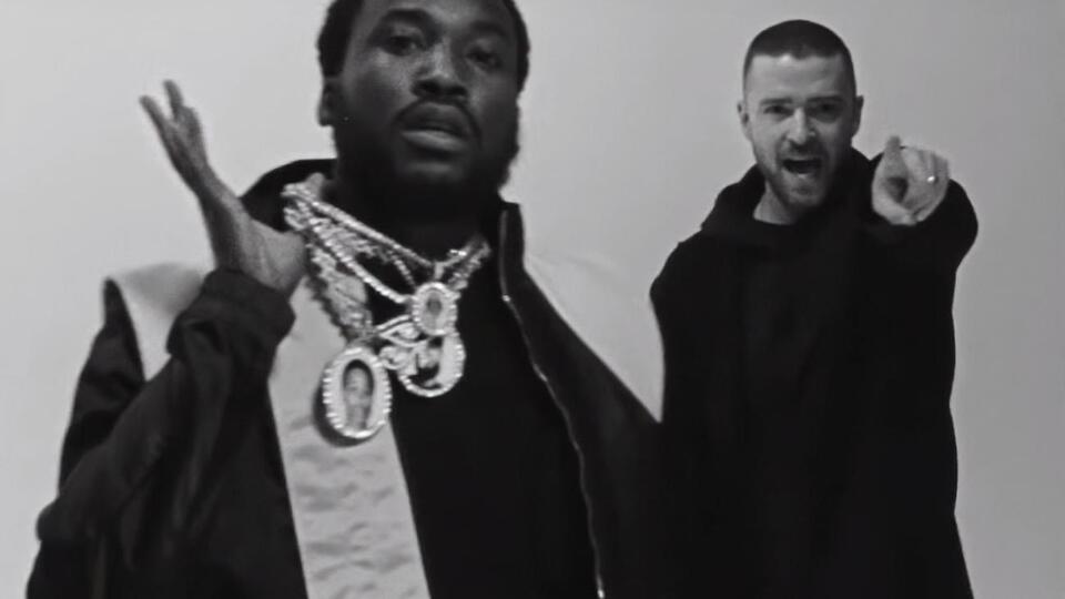 Meek Mill (на скріншоті зліва) в кадрі з'являється з кулоном, у центрі якого портрет репера Nipsey Hussle