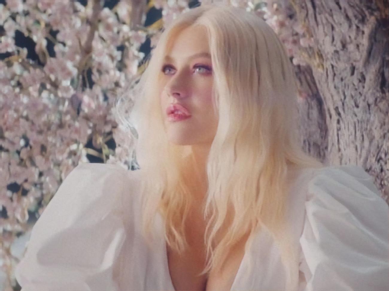 Агилера появляется в кадре в белом платье среди цветущих деревьев