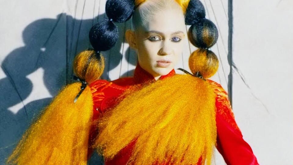 В ролике Grimes предстала в красном платье на фоне инопланетного пейзажа