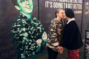 Эдвардс и Пиплс позируют на фоне изображения журналистки Лиры Макки, которая выступала за легализацию однополых браков